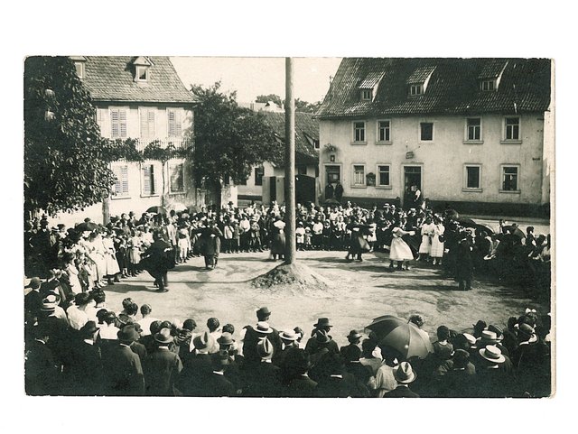 Plantanz um 1920 Der Erdhaufen um dem Planbaum deckte die hässlichen Befestigungspflöcken ab. Links das Pfarrhaus, rechts das Rathaus.