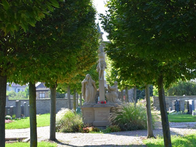 Friedhofsdenkmal zwischen grünen Bäumen