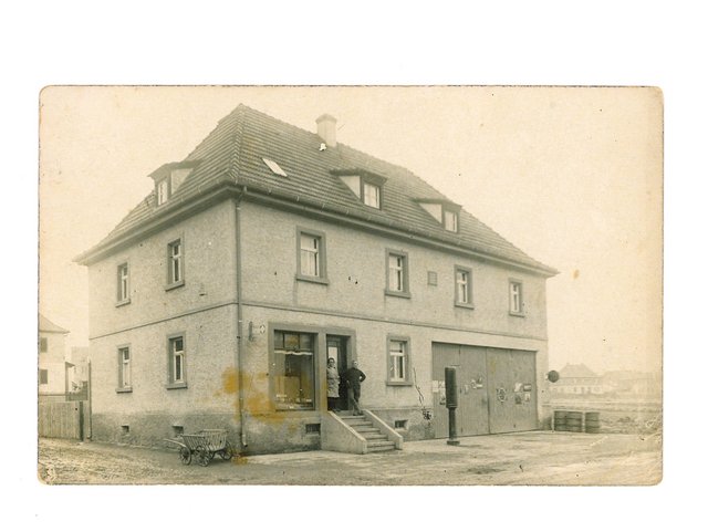 Gemischtes Warengeschäft von Julie Schuhmann, die das Geschäft später zusammen mit ihrem Ehemann Philip Schäfer führte. Rechts ist Sennfelds erste Tanksäule (Fa. Shell) ersichtlich. Rechts unten im Haus war der Fuhrpark der Gebrüder Schuhmann untergebracht. Aufnahme 1928.